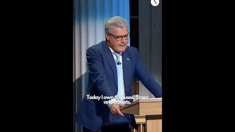 Reform leader Malcolm Offord stands at a podium, where he says he has six houses, six boats and five cars